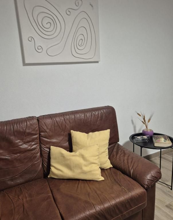 Sala com sofá de pele castanho e almofadas amarelas